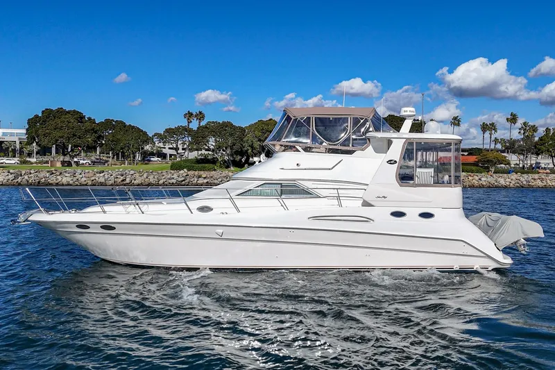 Slide: The Image of 1998 Sea Ray 420 Aft Cabin yacht cruising on a sunny day, coastal background. - 5