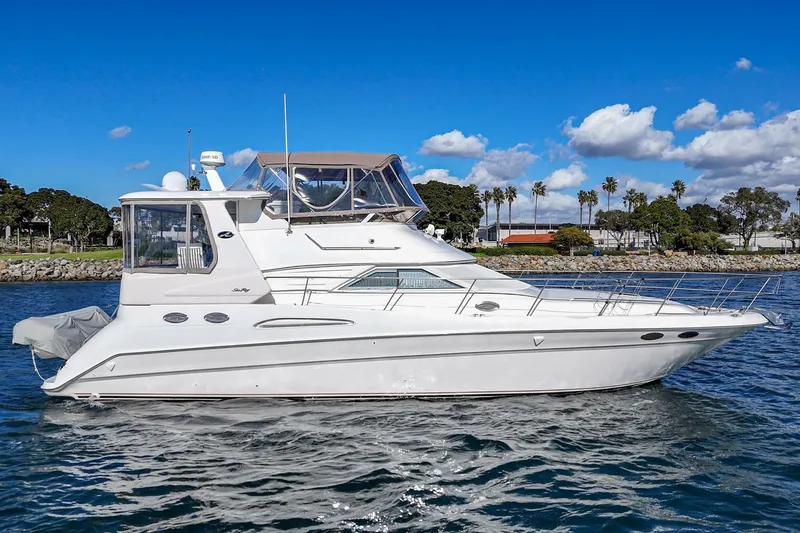 Slide: The Image of 1998 Sea Ray 420 Aft Cabin yacht on water, clear sky, palm trees in background. - 6