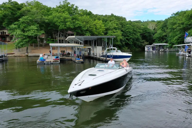 The Image of 2004 Cobalt 343 boat cruising near docks with lush green trees in the background. - 1