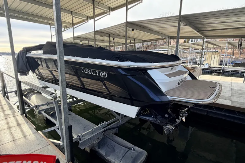 Slide: The Image of 2004 Cobalt 343 boat docked with cover, rear view, in a marina setting. - 17
