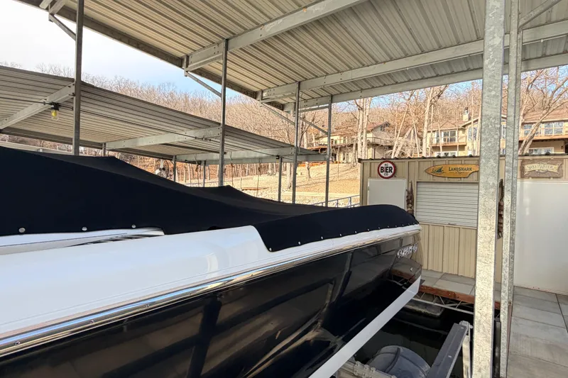 Slide: The Image of 2004 Cobalt 343 boat docked under covered marina, surrounded by trees and buildings. - 21