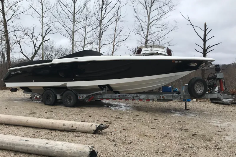Slide: The Image of 2004 Cobalt 343 boat on trailer, parked outdoors near leafless trees. - 4