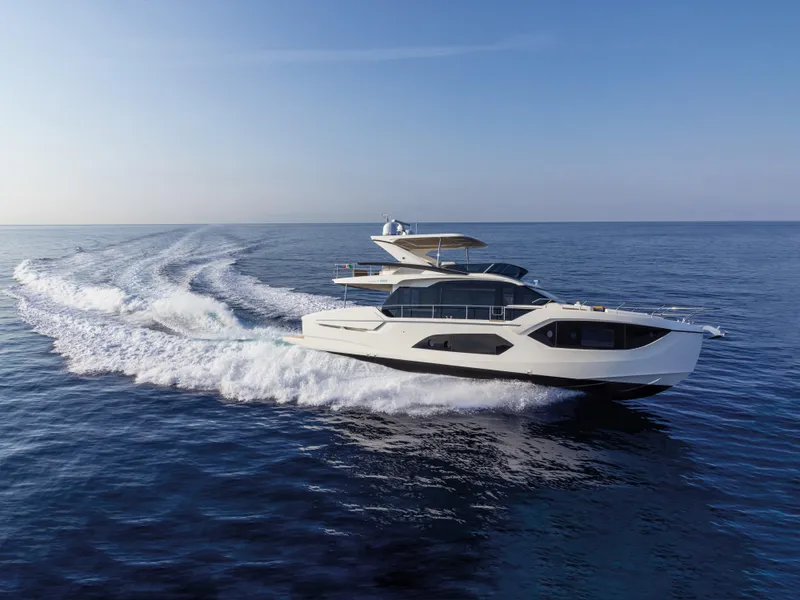 The Image of 2025 Absolute 60 Fly Co Ownership yacht cruising on open sea under clear blue sky. - 0