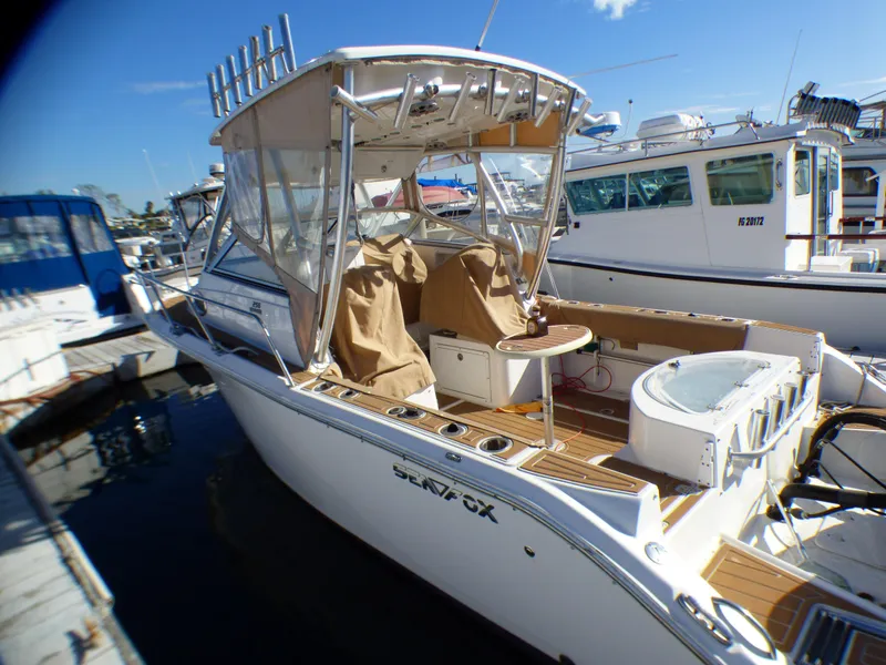 Slide: The Image of 2016 Sea Fox 256 Voyager boat docked at marina, featuring covered seating and fishing equipment. - 11