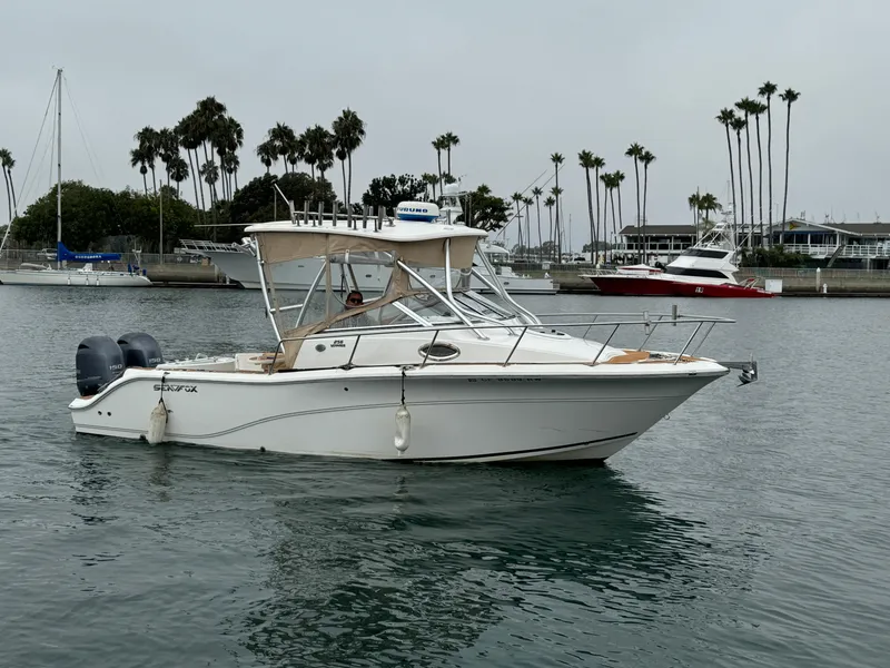 Slide: The Image of 2016 Sea Fox 256 Voyager boat on calm water near a marina with palm trees. - 5