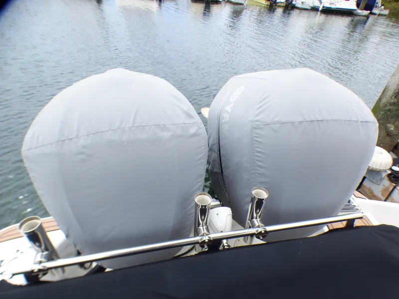 Slide: The Image of 2004 Robalo R265 Walkaround with covered dual outboard motors at a dock. - 17