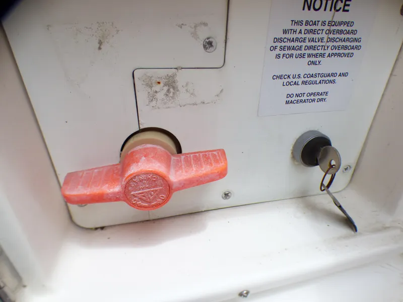 Slide: The Image of 2004 Robalo R265 Walkaround boat discharge valve with safety notice and key lock. - 18