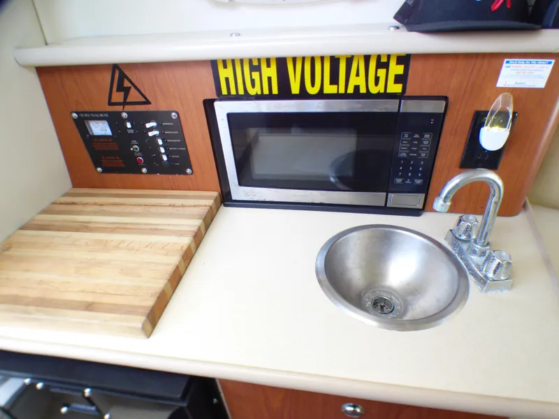 Slide: The Image of 2004 Robalo R265 Walkaround kitchen with microwave, sink, and cutting board. - 8