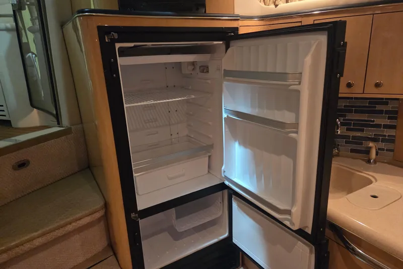 Slide: The Image of Open refrigerator inside 2000 Sea Ray 410 Sundancer yacht, showcasing interior storage space. - 25
