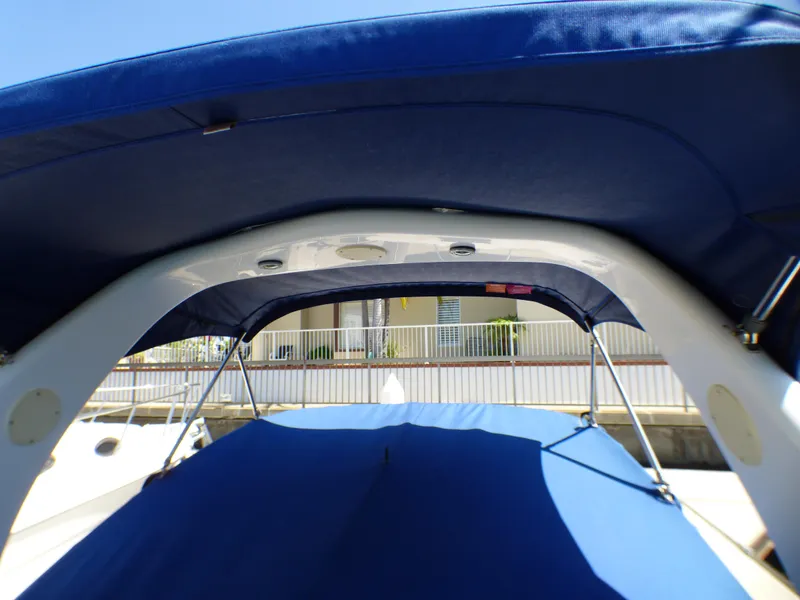 Slide: The Image of 2003 Sea Ray 260 Sundancer boat with blue canopy and sleek design. - 10