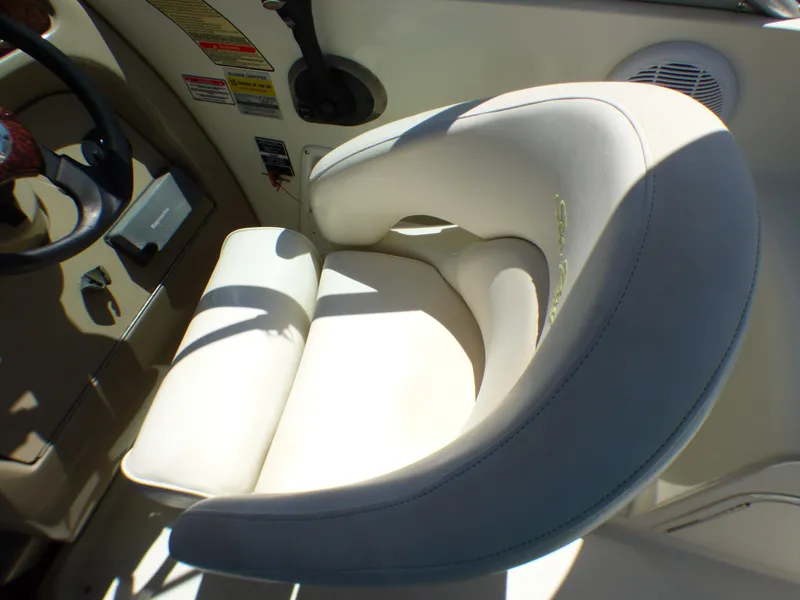 Slide: The Image of Captain's seat in 2003 Sea Ray 260 Sundancer boat cockpit, featuring beige upholstery. - 19