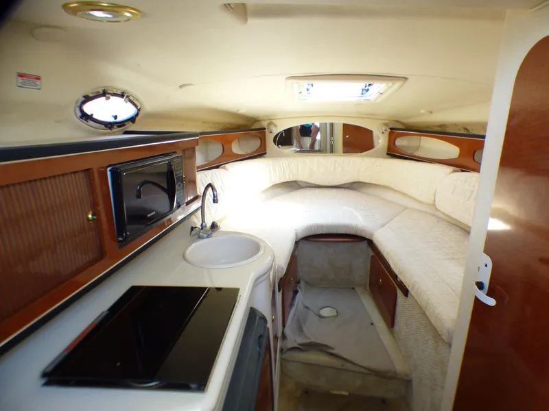Slide: The Image of 2003 Sea Ray 260 Sundancer cabin interior with kitchenette, sink, and cozy sleeping area. - 20