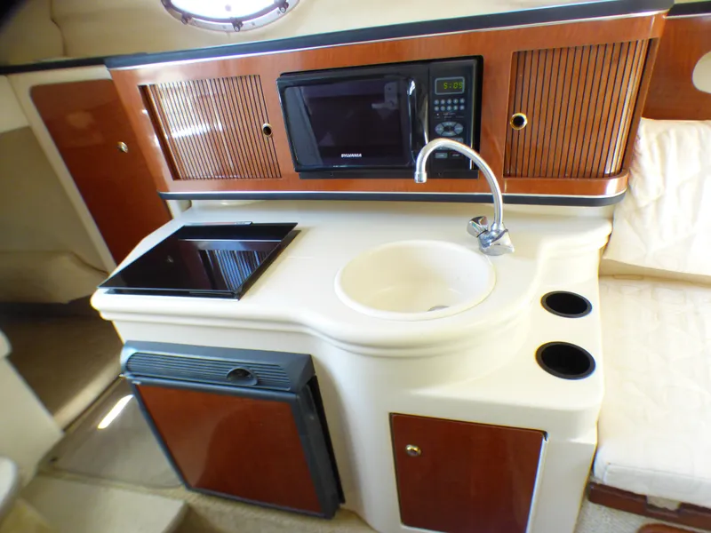 Slide: The Image of 2003 Sea Ray 260 Sundancer cabin kitchen with sink, microwave, and stove. - 21