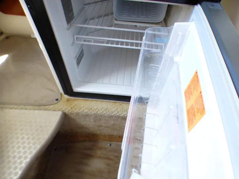 Slide: The Image of Open fridge inside 2003 Sea Ray 260 Sundancer boat, showing interior shelves. - 25