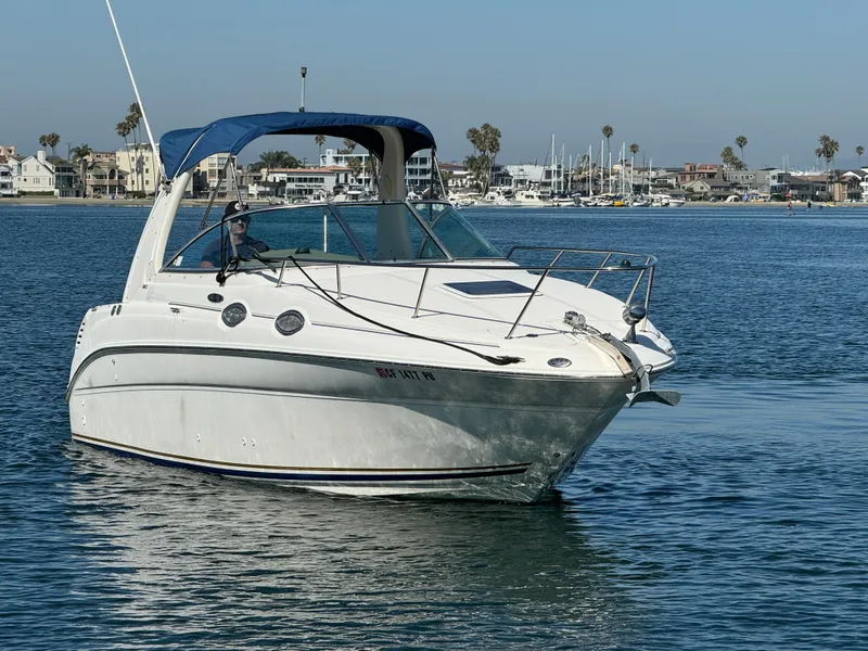 Slide: The Image of 2003 Sea Ray 260 Sundancer boat cruising on calm waters near a marina. - 5