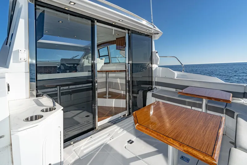 Slide: The Image of 2023 Cruisers Yachts 42 Cantius, elegant deck with wooden tables, ocean view. - 12