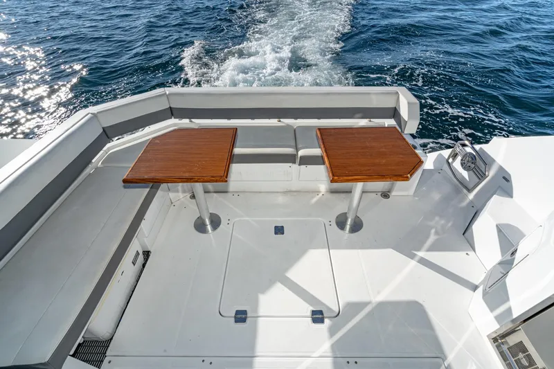 Slide: The Image of 2023 Cruisers Yachts 42 Cantius deck with seating and tables, cruising on open water. - 13