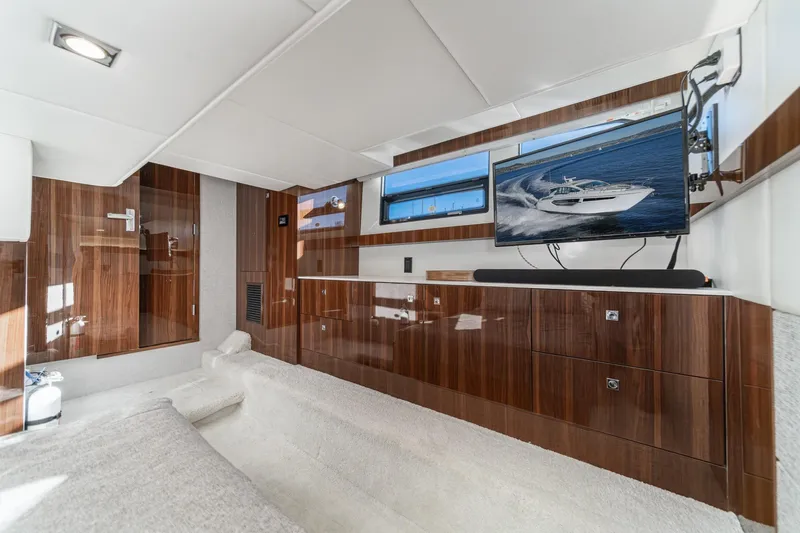 Slide: The Image of Luxurious interior of 2023 Cruisers Yachts 42 Cantius with sleek wood finishes and modern TV setup. - 37