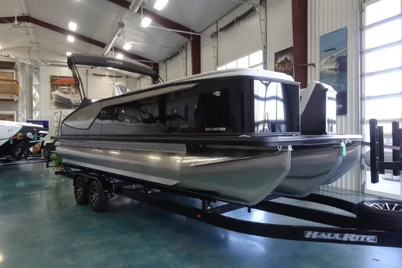 The Image of 2026 Harris Sunliner 250 pontoon boat displayed indoors on a trailer. - 0