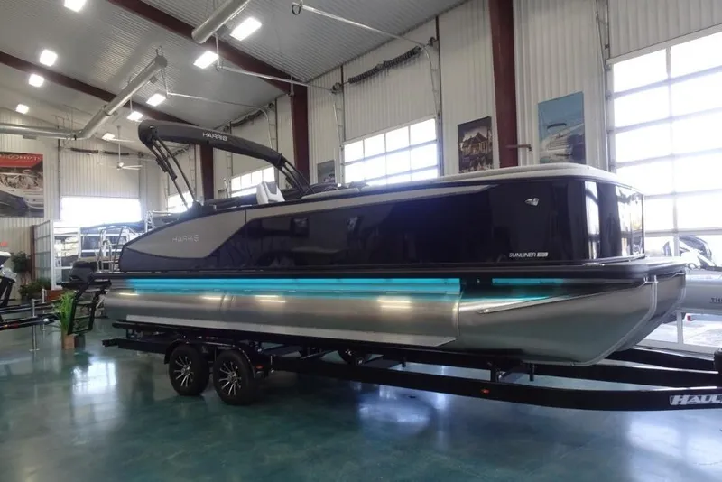 Slide: The Image of 2026 Harris Sunliner 250 pontoon boat displayed indoors on a trailer. - 1