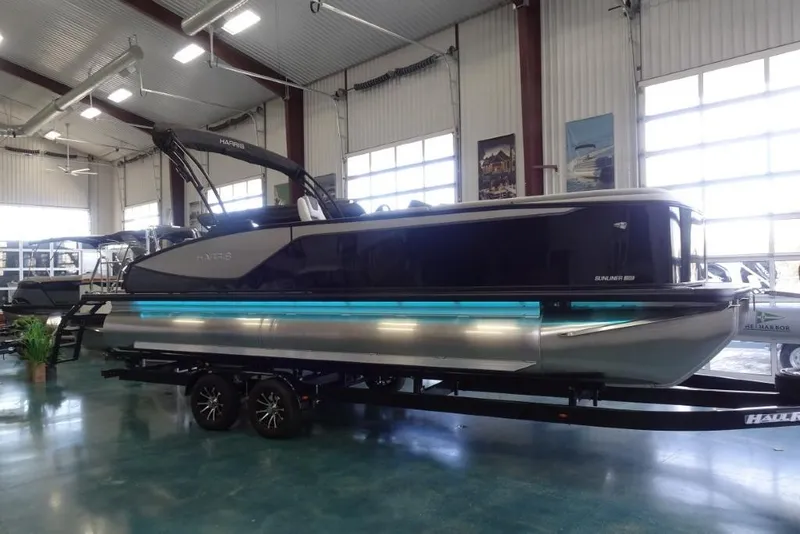 Slide: The Image of 2026 Harris Sunliner 250 pontoon boat displayed indoors on a trailer. - 2