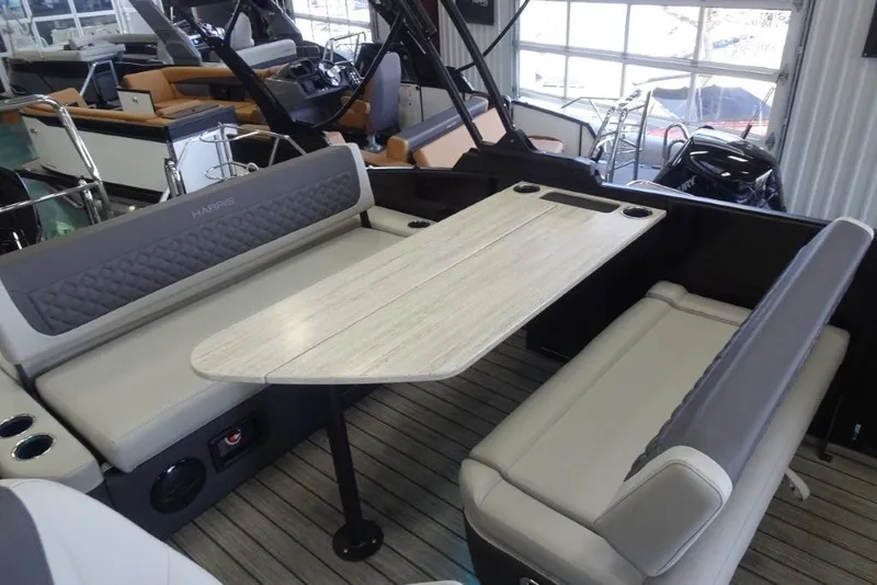 Slide: The Image of 2026 Harris Sunliner 250 boat interior with seating and table in showroom. - 25