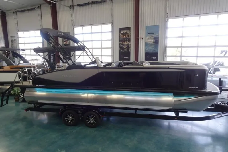 Slide: The Image of 2026 Harris Sunliner 250 pontoon boat displayed indoors on a trailer. - 3