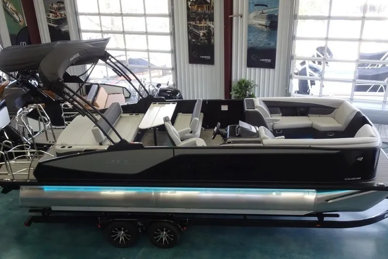 Slide: The Image of 2026 Harris Sunliner 250 pontoon boat displayed indoors with sleek design and modern seating. - 33