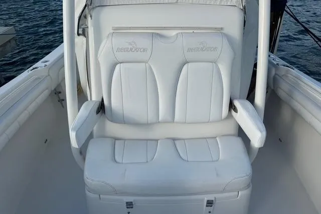 Slide: The Image of 2017 Regulator 25 boat with white cushioned seating and armrests on deck. - 23