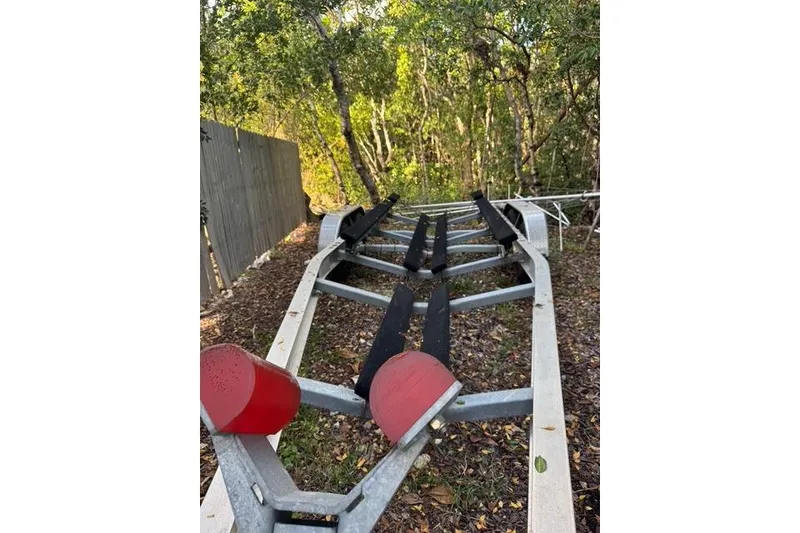 Slide: The Image of Empty boat trailer for 2017 Regulator 25, parked outdoors near trees. - 43