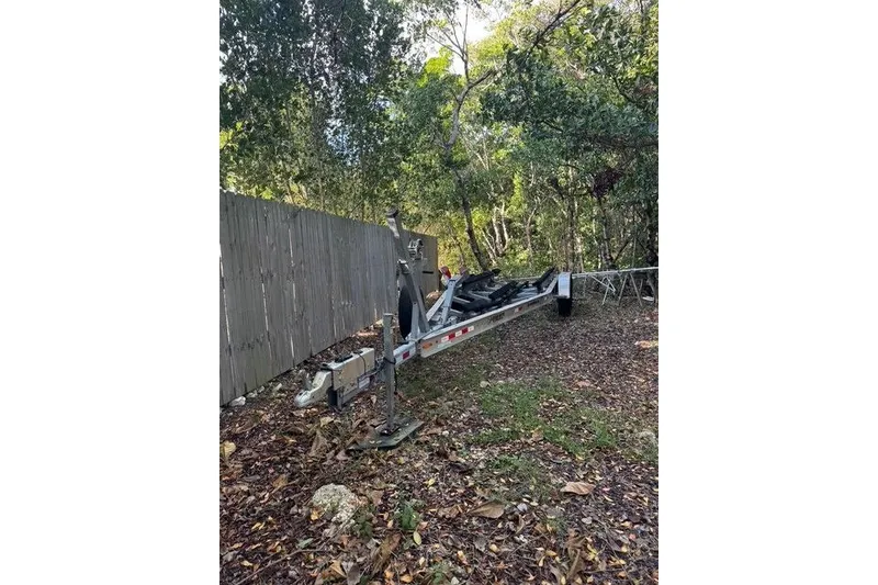 Slide: The Image of Trailer for 2017 Regulator 25 boat parked outdoors near a wooden fence. - 46