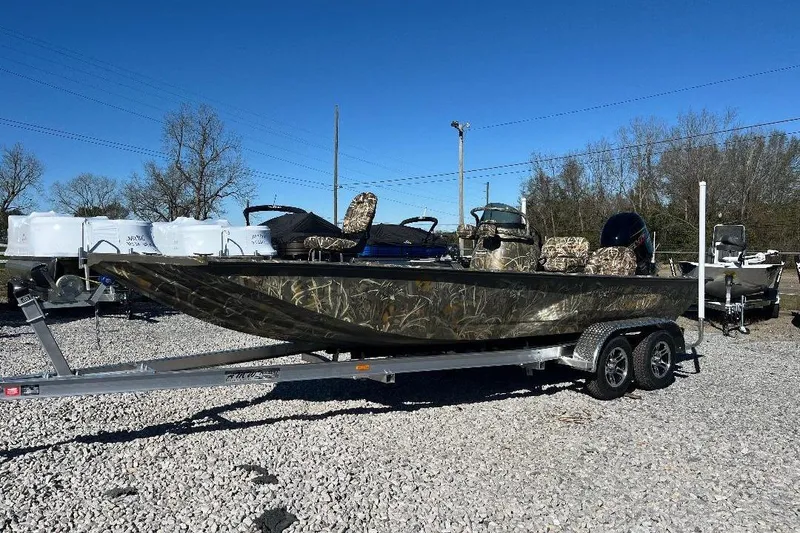 Slide: The Image of 2026 War Eagle 2170 Blackhawk boat on trailer, camo design, parked on gravel lot. - 0