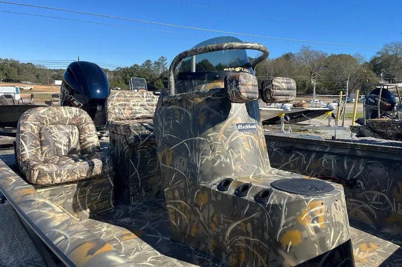 Slide: The Image of 2026 War Eagle 2170 Blackhawk boat with camouflage design and seating, parked outdoors. - 18
