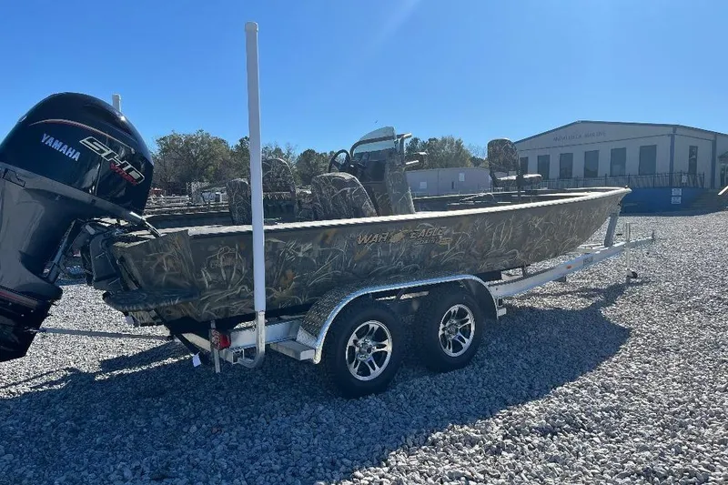 Slide: The Image of 2026 War Eagle 2170 Blackhawk boat on trailer with Yamaha motor, parked on gravel. - 2