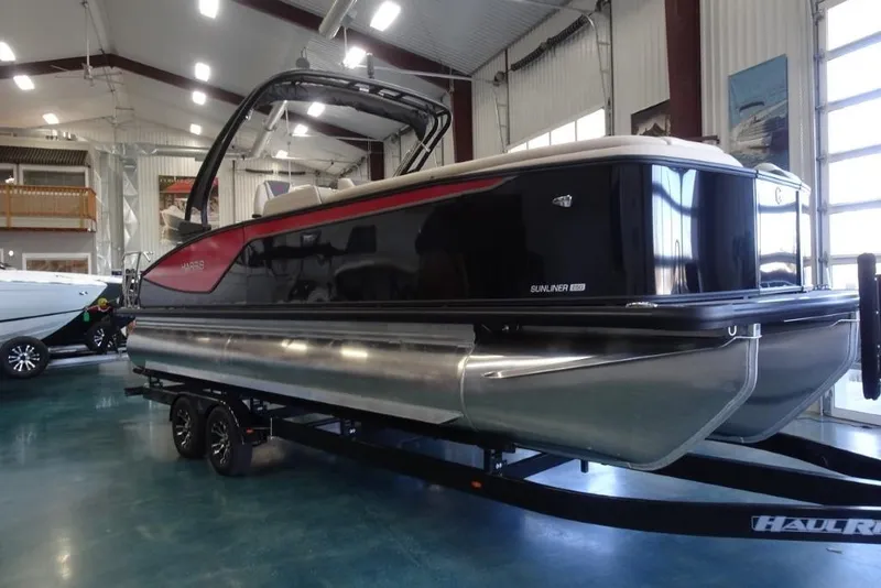 The Image of 2026 Harris Sunliner 250 Sport pontoon boat in showroom, sleek design on trailer. - 0