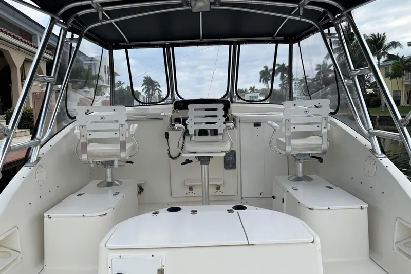 Slide: The Image of 1995 Pursuit 3000 Express boat interior with helm and seating, docked near palm trees. - 16