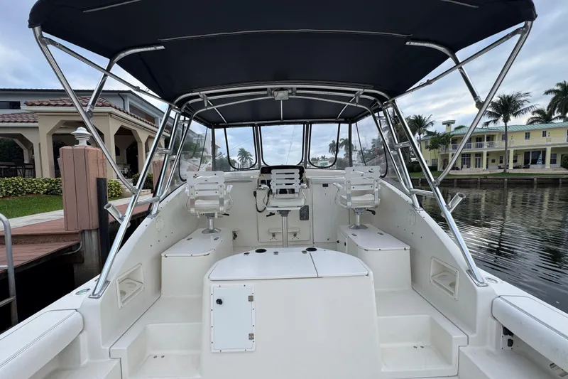 Slide: The Image of 1995 Pursuit 3000 Express boat interior with seating, docked near waterfront homes. - 18