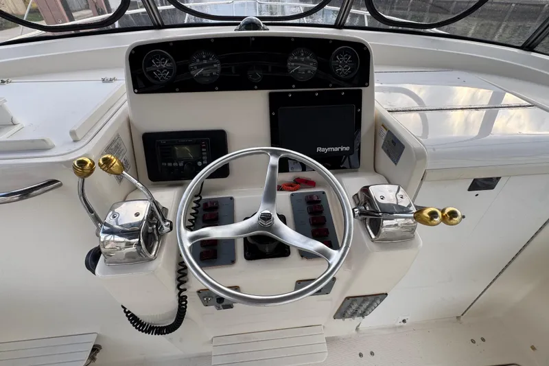 Slide: The Image of 1995 Pursuit 3000 Express boat helm with steering wheel and control panel. - 19