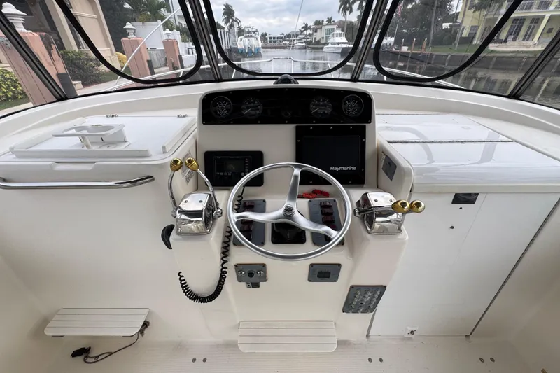 Slide: The Image of 1995 Pursuit 3000 Express boat helm with steering wheel and navigation controls. - 20
