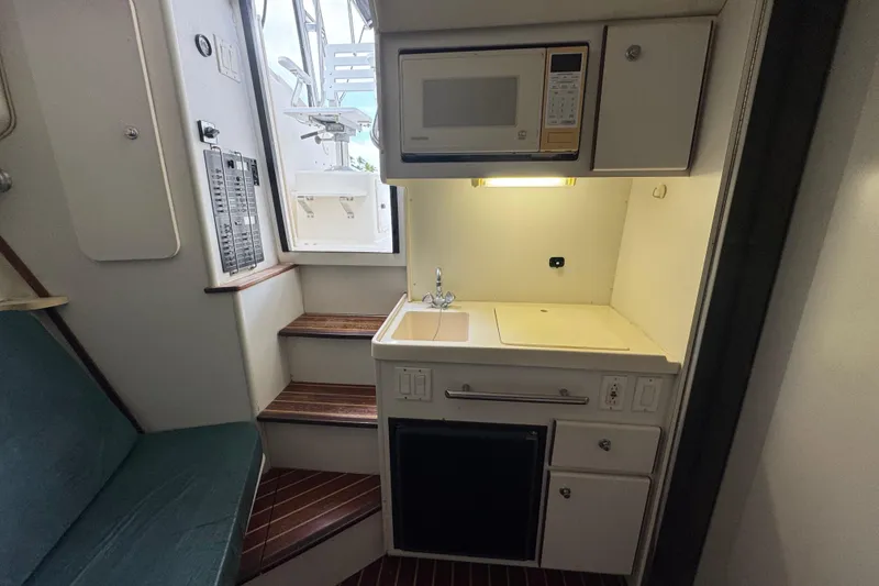 Slide: The Image of 1995 Pursuit 3000 Express boat interior with kitchenette, microwave, and seating area. - 25
