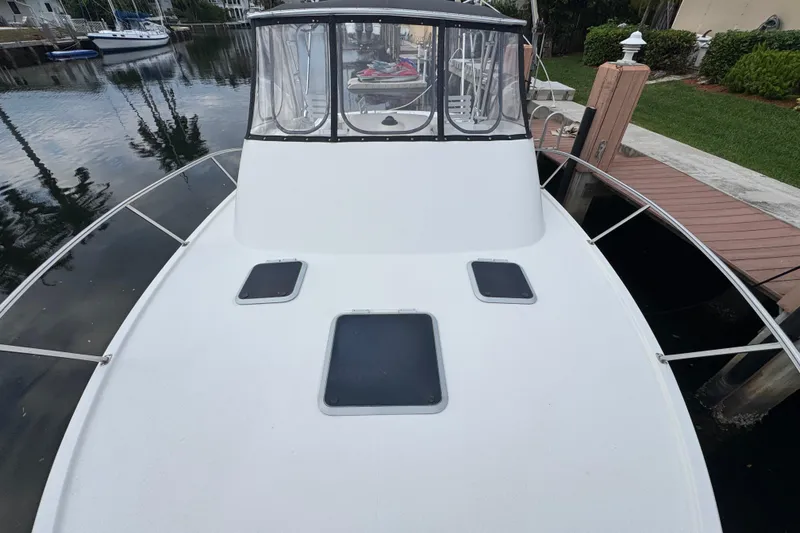 Slide: The Image of 1995 Pursuit 3000 Express boat docked, featuring a spacious deck and clear canopy. - 29