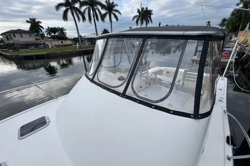Slide: The Image of 1995 Pursuit 3000 Express boat docked by palm trees and waterfront homes. - 32