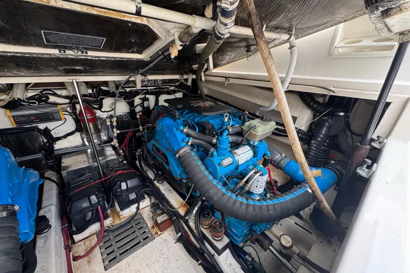Slide: The Image of Engine room of a 1995 Pursuit 3000 Express boat, featuring blue engines and wiring. - 33
