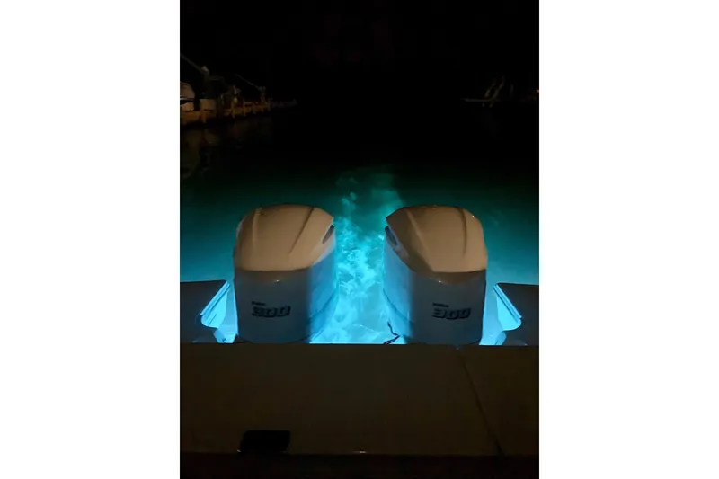 Slide: The Image of Twin 300 horsepower engines on a 2020 Pursit DC 325 boat, illuminated at night. - 21