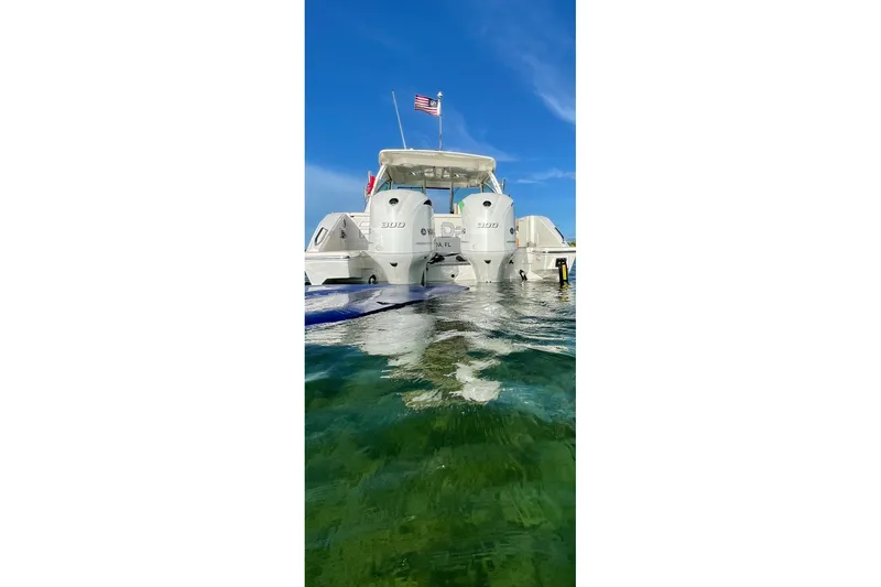 Slide: The Image of 2020 Pursit DC 325 boat with dual engines on clear water, American flag waving. - 4