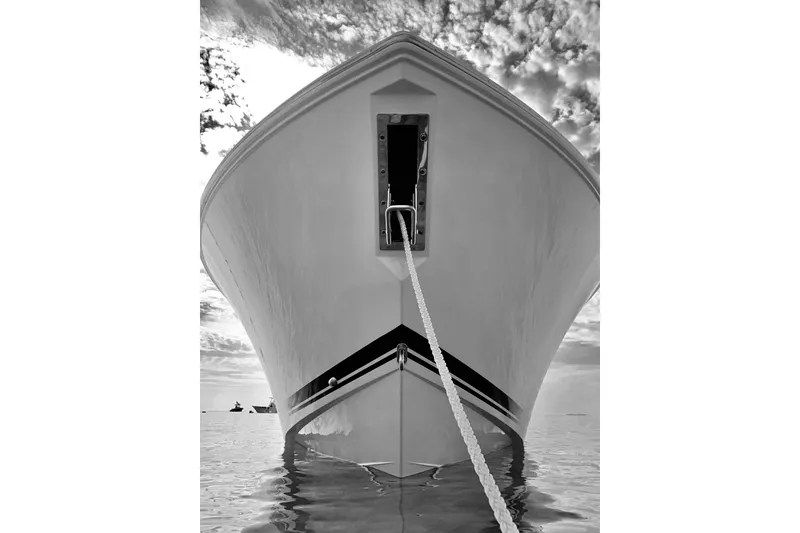 Slide: The Image of Front view of 2020 Pursit DC 325 boat anchored on calm water, under a cloudy sky. - 5