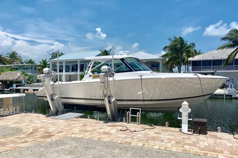 Slide: The Image of 2020 Pursit DC 325 boat docked at a marina with palm trees and blue sky. - 6
