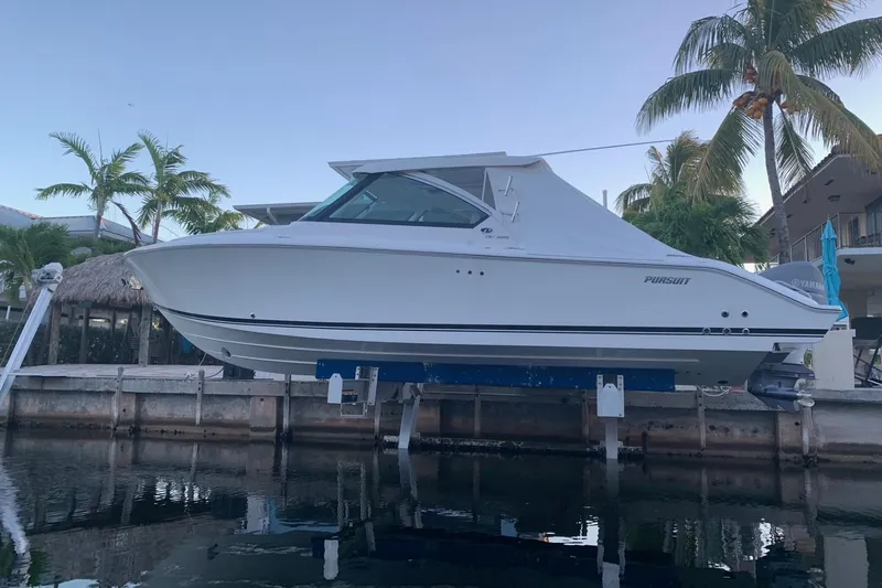 Slide: The Image of 2020 Pursuit DC 325 boat docked near palm trees and waterfront homes. - 7