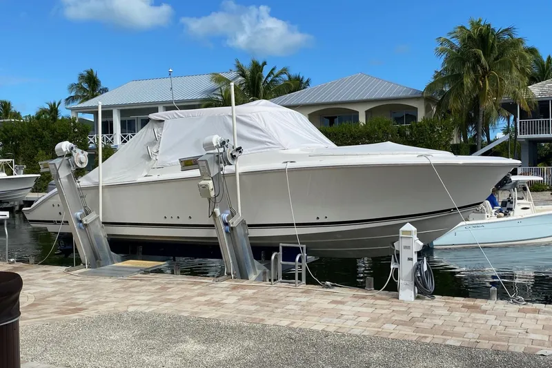 Slide: The Image of 2020 Pursit DC 325 boat docked, covered, with tropical background and clear sky. - 8
