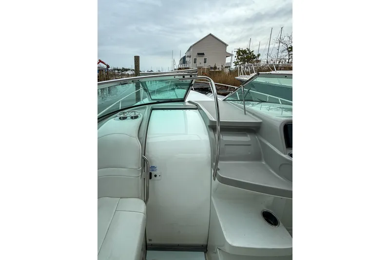 Slide: The Image of 2004 Formula 330 Sun Sport boat interior with seating and railing, docked near a house. - 12